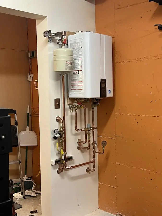 Plumbing technician inspecting water heater connections in Ash
